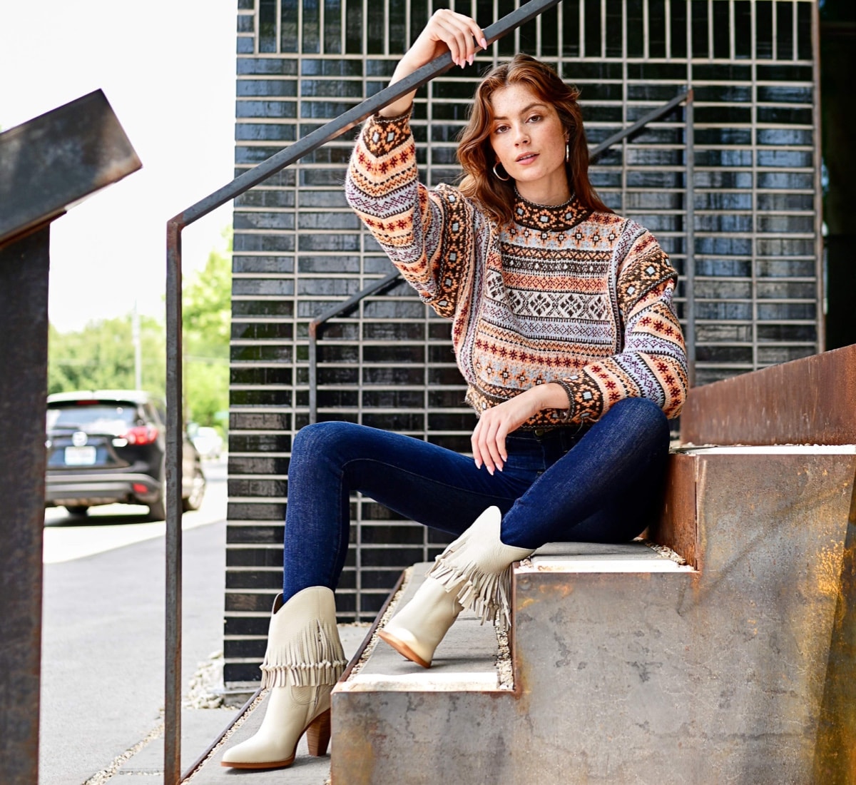 a model sitting on concrete stairs wearing the Donna western boot